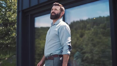 Likable Caucasian Man in Shirt and Trousers Going Out of House Looking Away Breathing Fresh Air
