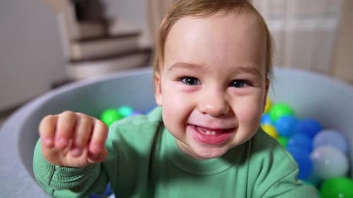 Smiling Infant Playing in a Colorful Ball Pit