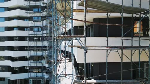 Baufortschritt eines modernen Wohnhauses mit Gerüst in einem belebten Stadtgebiet