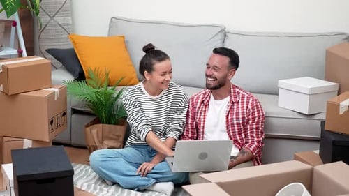 Young Renters in New Apartment Laptop Amidst Boxes Shop Online or Manage Their Move