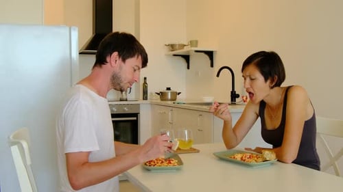 Couple Talking While Eating Meal in Kitchen
