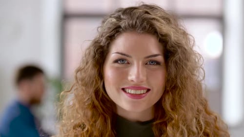 Attractive Woman Smiling in Office Environment with Man