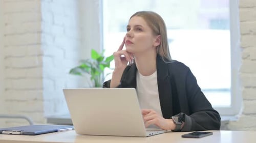 Denkende Geschäftsfrau hat eine neue Idee, während sie am Laptop arbeitet