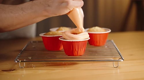 Cupcakes Being Decorated with Light Orange Frosting