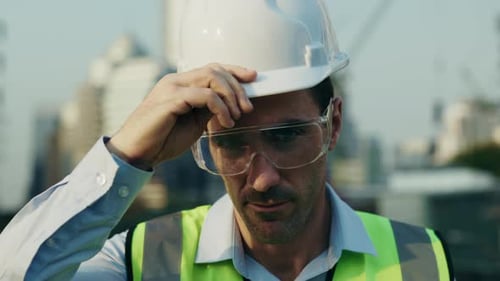 Portrait of Man Engineer Putting on Helmet Looking at Camera