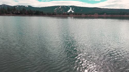 Drohnenflug in niedriger Höhe über dem Big Bear Lake, der die gewellte Wasseroberfläche und die entfernte Küstenlinie einfängt