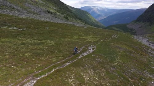 Drone shot passing by solo hiker in beautiful mountain valley
