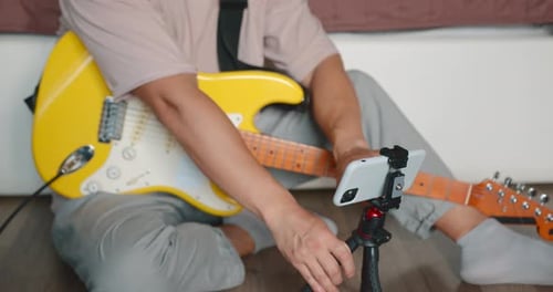 Musician Adjusts Smartphone with Electric Guitars