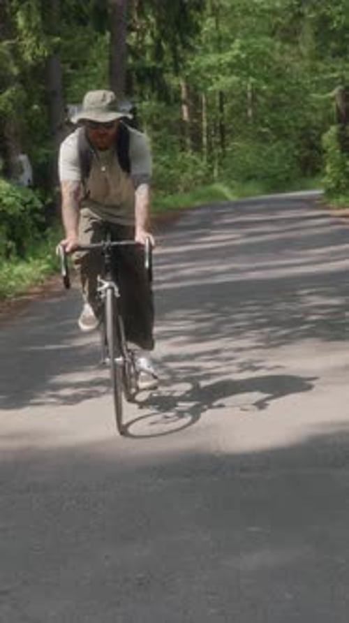 Cyclist Rides Toward Camera Through Forest Road