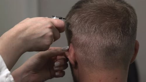 Nahaufnahme eines Friseurs, der mit fachkundiger Hand einen präzisen Kurzhaarschnitt akribisch modelliert und mischt
