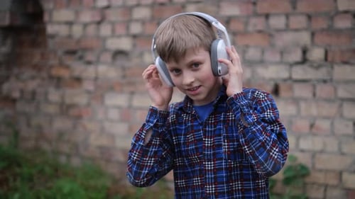 Boy Listens to Music With Headphones by Wall