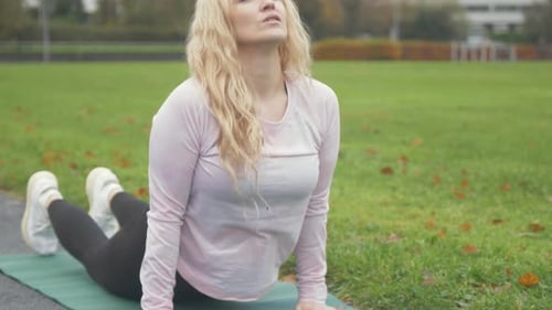 Une femme effectue la pose de yoga Bhujangasana Cobra dans le parc