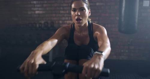 A young woman working out with a rowing machine in a gym