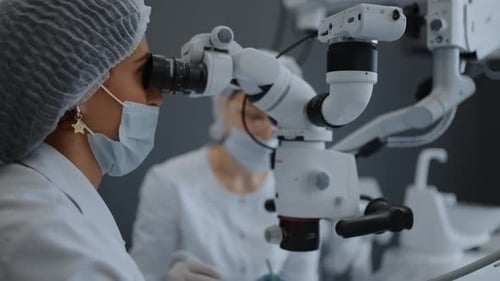 Dentista femenina mirando el microscopio quirúrgico durante el examen o el tratamiento de los pacientes