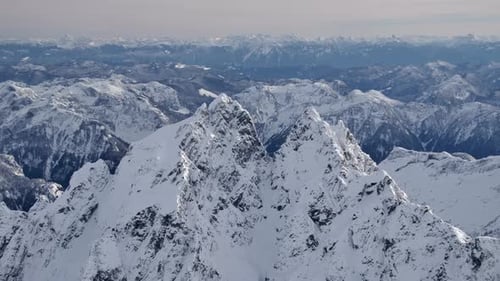 Steiler, zerklüfteter Berggipfel und bergige Winterlandschaft AUS DER LUFT