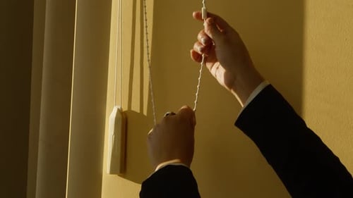 Hands Adjusting Window Blinds for Privacy