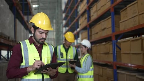 Blue collar workers are working at warehouse.