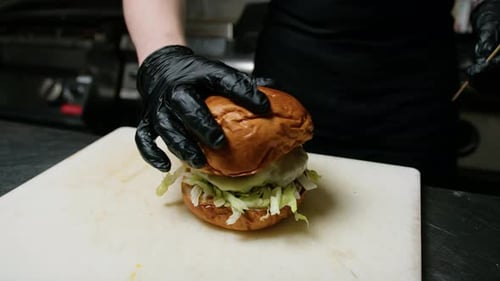 Chef Assembling Gourmet Burger with Toppings