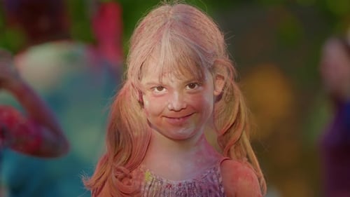 Little Girl in Colorful Paint at Holi Festival Happy and Contented Looking at Camera and Smiling