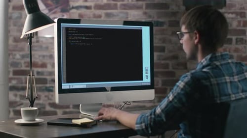 Young Caucasian Programmer Working on a Computer at His Home Office.