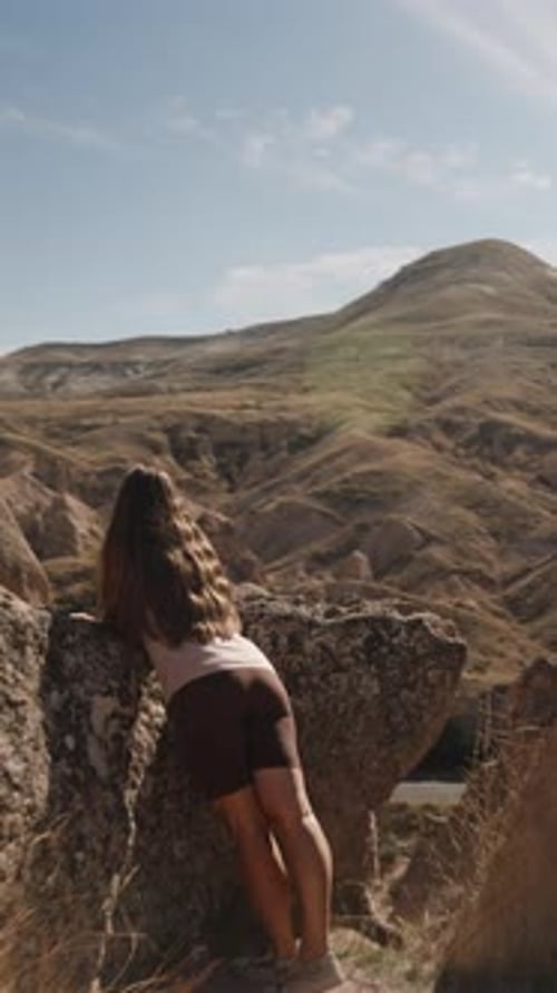 Vertikales Video. Die Kamera nähert sich einer jungen Frau, die die Aussicht in der Nähe eines Steins bewundert
.