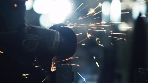 Ein Arbeiter mit Winkelschleifer bearbeitet die Metallbearbeitung im industriellen Umfeld. Funkenreflexionen