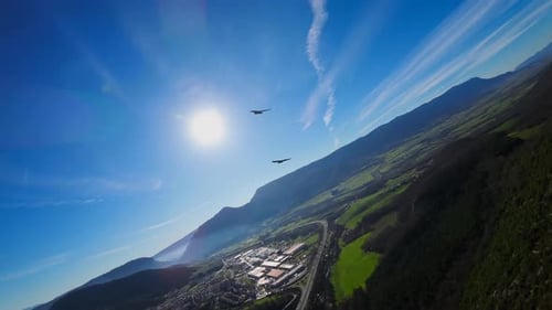 Birds flying in slow motion over the mountain, with the blue sky and the sun in the background. Imag