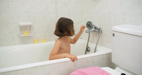 Child Plays in Tub with Rubber Ducks