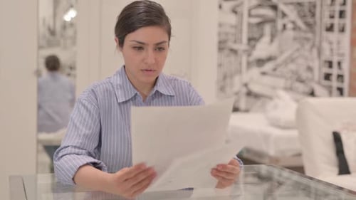 Woman Reviews Documents at Table in Home Office