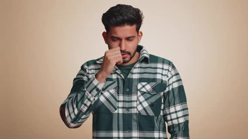 Young Man Coughing and Holding Forehead Indoors