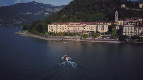Drone Shot of Small Boat Sails Up to Villa Yacht on Lake Como Moored to House Aerial View of Yacht
