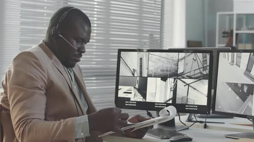 Man Monitors Security Footage in Bright Office Setting