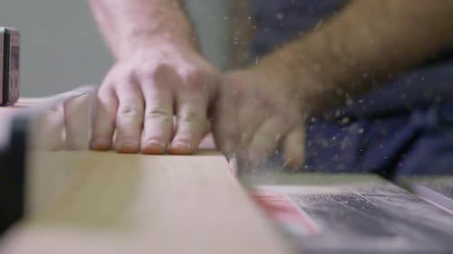 Man cuts wood on a table saw in his shop