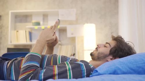 Young Adult Using Mobile Phone on Bed