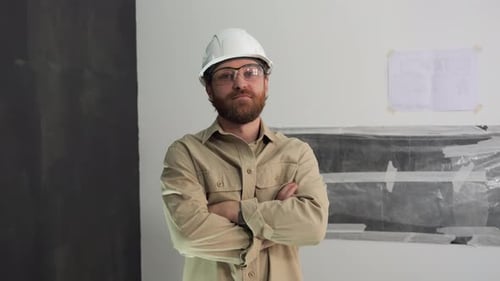 A Young Male Engineer Looks Into the Camera with His Arms Crossed on His Chest