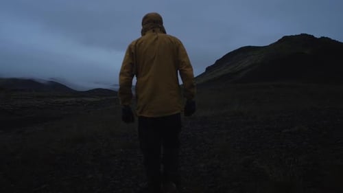 iceland, person walking through barren volcanic landscape at night, wide angle lens shot,