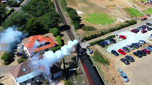 Vista aérea de um trem a vapor passando por uma passagem de nível em Sheringham, Norfolk, Reino Unido.