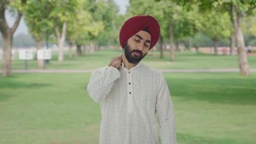 Sick Sikh Indian man suffering from neck pain in park