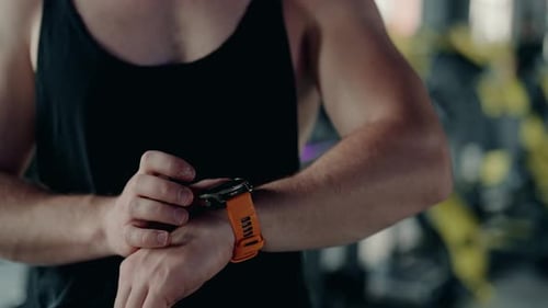 Muskulöser Mann mit Smartwatch im Fitnessstudio