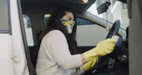 Woman Wipes Car Steering Wheel with Sanitizer
