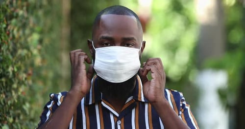 Man Puts on Protective Face Mask Outdoors