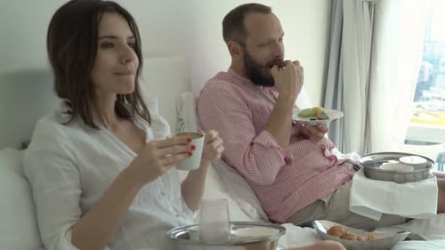 Couple Eating Fruit Breakfast in Bed at Hotel