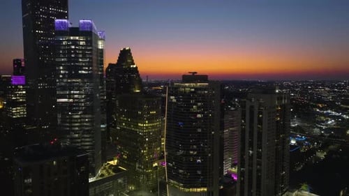 Aerial view rising toward illuminated skyscrapers, evening in Houston, USA