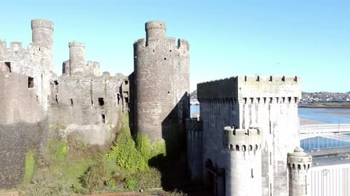 Medieval Conwy castle Welsh market town towers aerial view historical harbour low rising shot