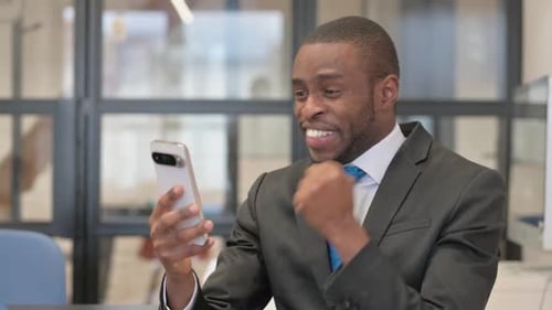 Excited Man Receives Good News on Smartphone in Office