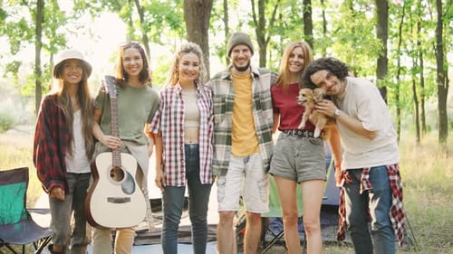 A Group of Cheerful Friends Tourists are Relaxing in a Green Forest with Tents an Acoustic Guitar