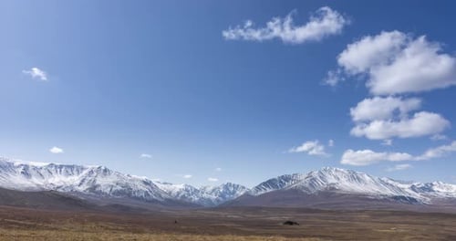Timelapse of Sun Movement on Crystal Clear Sky with Clouds Over Snow Mountain Top Yellow Grass at