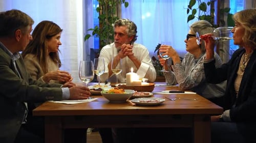 Adults gather around dinner table for conversation