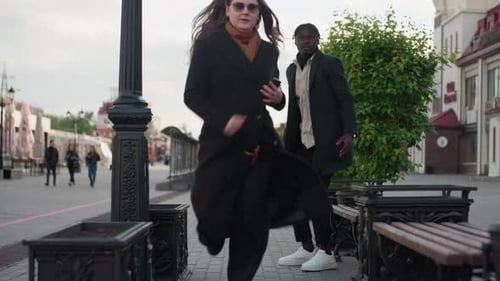 Young Girl Grabs Phone And Bag From Boyfriend Sitting On Street Bench