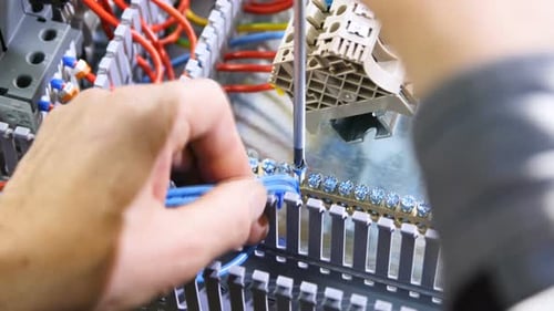 Technician Connects Wires in Electrical Control Panel